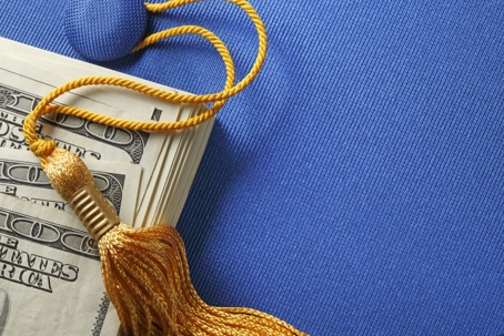 dollar bills on top of a blue graduation cap